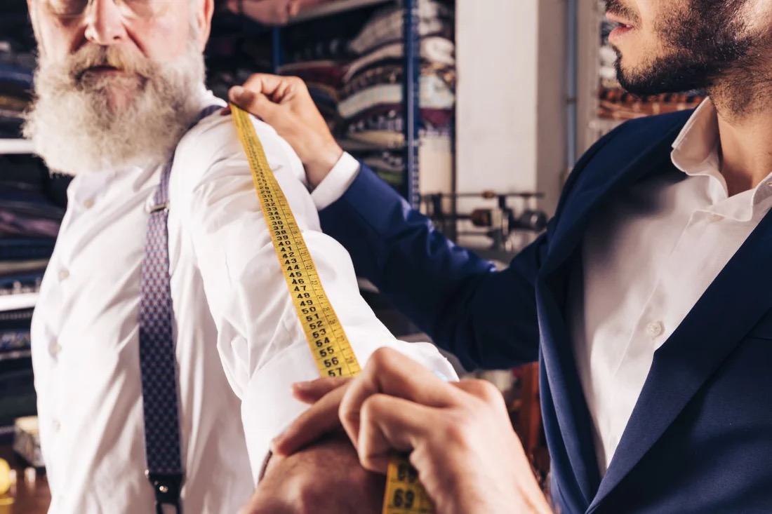 A tailor measuring a client during a bespoke fitting